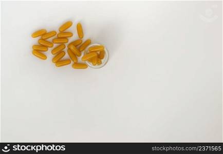 Golden oil capsules in glass bottle on white background. Nutritional supplements, Health care concept. Top view, Copy space, Selective focus.