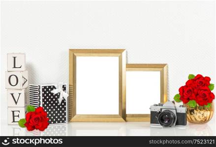 Golden picture frames, red rose flowers, vintage camera. Retro style decorations with space for your photo