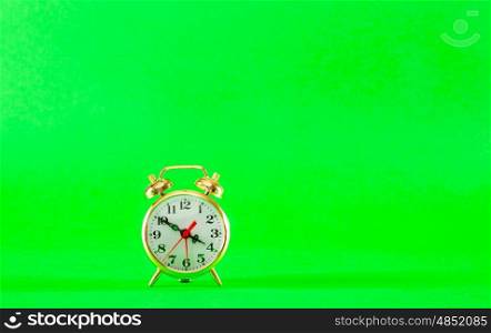 Golden retro style alarm clock over green background