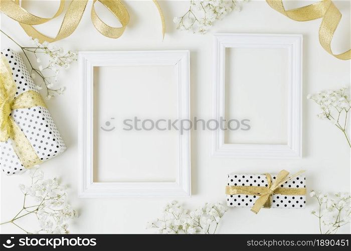 golden ribbon gift boxes baby s breath flowers near wooden frame white backdrop