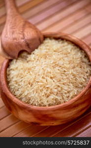 golden rice on wooden plate on wooden background