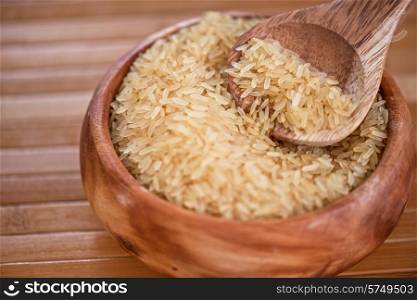 golden rice on wooden plate on wooden background. golden rice