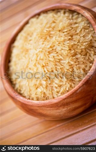 golden rice on wooden plate on wooden background. golden rice