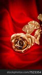 Golden rose flower on red satin background