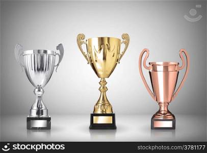 golden, silver and bronze trophies on gray background