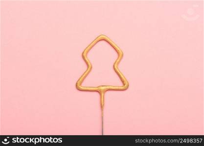 Golden sparkler in shape of christmas tree on pink background. New year concept.