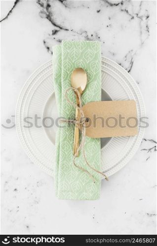 golden spoon napkin tied with string white plate against textured backdrop