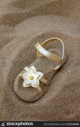 golden star sandal buried in summer beach sand vacation metaphor