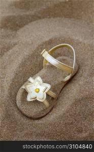 golden star sandal buried in summer beach sand vacation metaphor