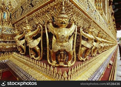 Golden statues carved on walls of a temple, Wat Phra Kaeo, Bangkok, Thailand