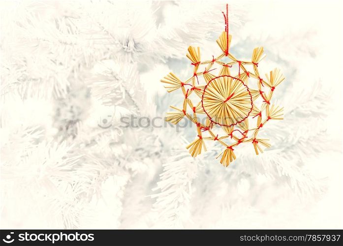 Golden straw ornament decorates the white christmas tree - vintage tinted