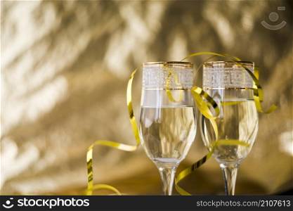 golden streamers transparent champagne glasses against blurred background