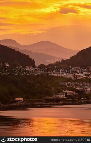 golden sunrise with little houses on hills in norway