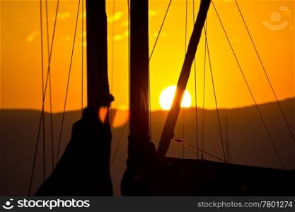 Golden sunset and sailboats - ropes, sail and sun behind the mountain
