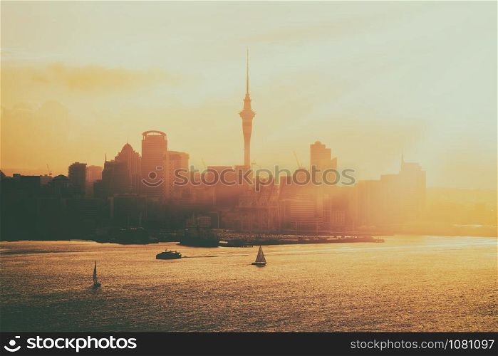 Golden sunset at Auckland city skyline with silhouette of city center and Auckland Sky Tower, the iconic landmark of Auckland, New Zealand.