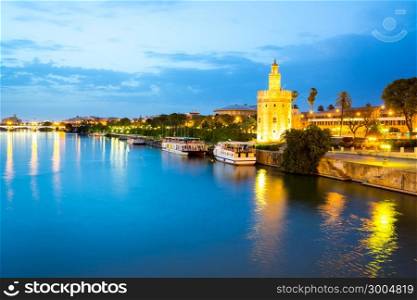 Golden Tower with cityscape and river of Sevilla at night Seville, Spain