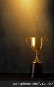 Golden trophy cup on dark table with rays of light and glitter dust dark background