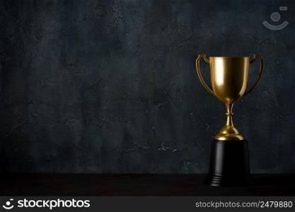 Golden trophy cup on table dark background with copy space