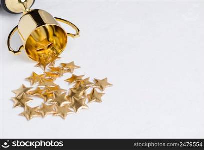 Golden trophy cup with golden shiny stars on white textured background with copy space
