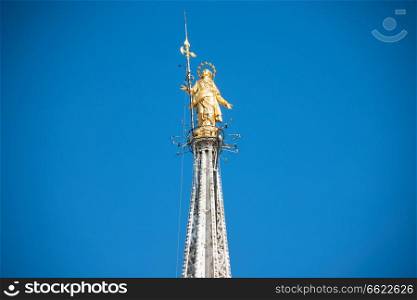 Golden Virgin Mary statue on top roof of Duomo cathedral in Milan, Italy