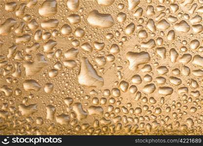 golden water drops over brushed metal background