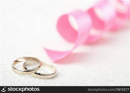 Golden wedding rings and pink ribbon