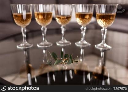 golden wedding rings on a glass table with eucalyptus. champagne glasses on the background. selective focus.. golden wedding rings on a glass table with eucalyptus. champagne glasses on the background. selective focus