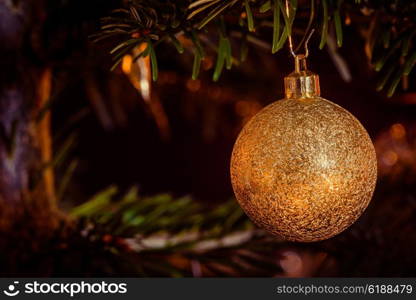 Golden Xmas bauble hanging on a Christmas tree