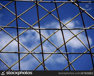Goldgitter. Golden mesh in front of blue sky and clouds