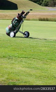 Golf bag and cart on green