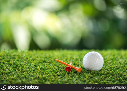 golf ball and wooden tee on grass