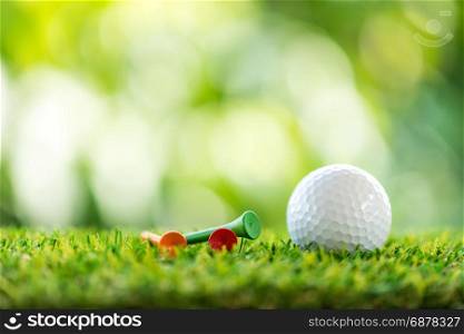 golf ball and wooden tee on grass