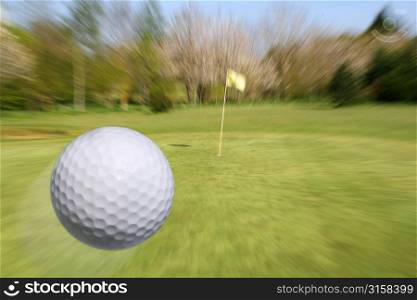 Golf ball flying towards hole