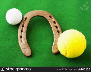 Golf ball, horseshoe, tennis ball over green background, horizontal image