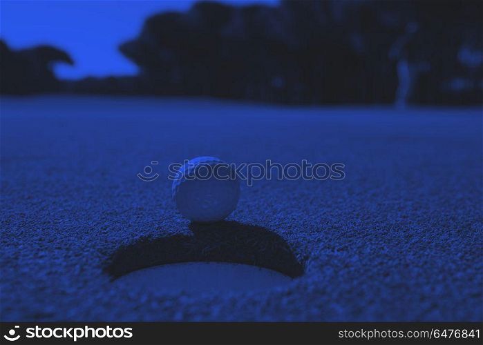golf ball in the hole. golf ball on edge of course hole representing achivement and success business concept duo tone