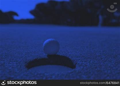 golf ball in the hole. golf ball on edge of course hole representing achivement and success business concept duo tone
