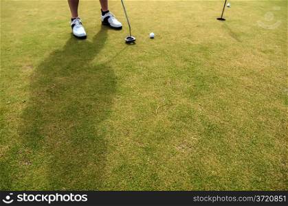 Golf ball on a green, in front of the hole,