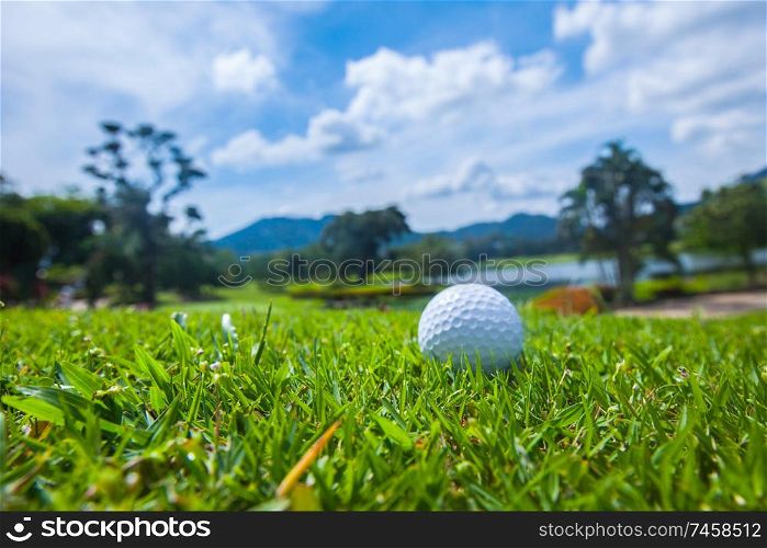 Golf ball on course, beautiful landscape with lake and mountains on background. Golf ball on course