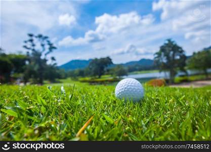 Golf ball on course, beautiful landscape with lake and mountains on background. Golf ball on course