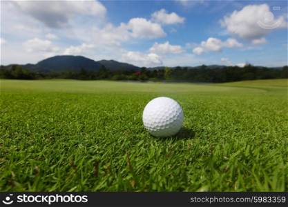 Golf ball on course. Golf ball on green course grass close up and the flag