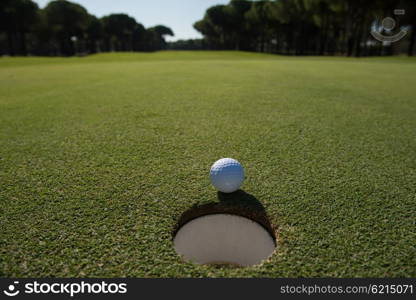 golf ball on edge of course hole representing achivement and success business concept