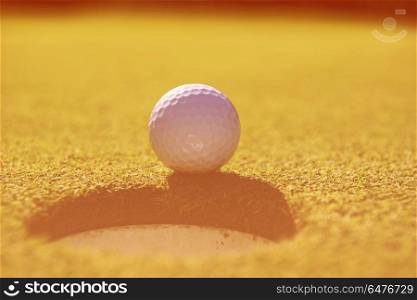 golf ball on edge of course hole representing achivement and success business concept. golf ball in the hole