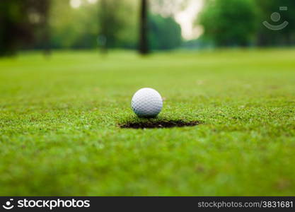 Golf ball on green meadow. golf ball on lip of cup