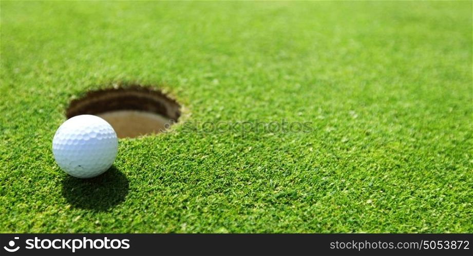 golf ball on lip of cup close up. golf ball on lip of cup