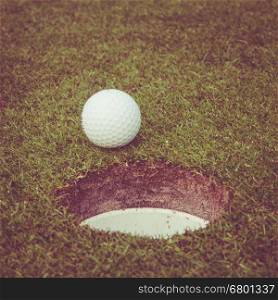 golf ball on lip of cup. Golf ball on green grass in golf course. Vintage, retro style