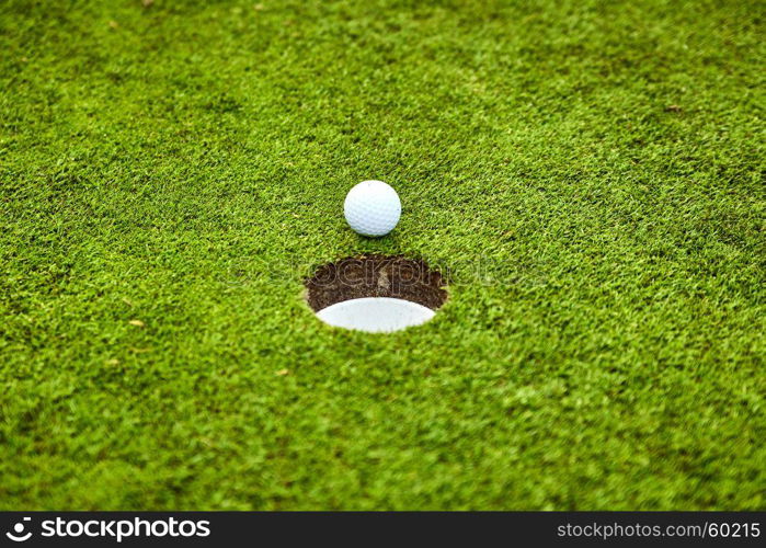 Golf ball on the green. golf ball on lip of cup