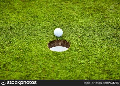 Golf ball on the green. golf ball on lip of cup
