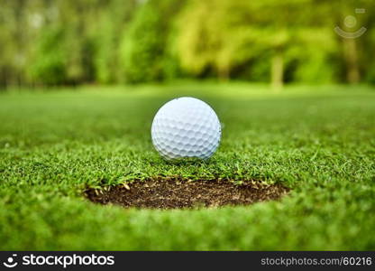 Golf ball on the green. golf ball on lip of cup