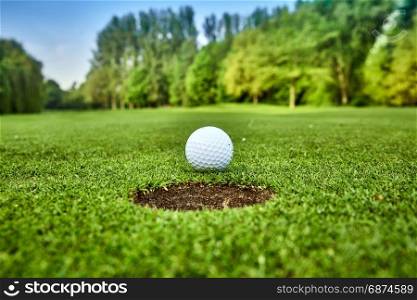Golf ball on the green. golf ball on lip of cup