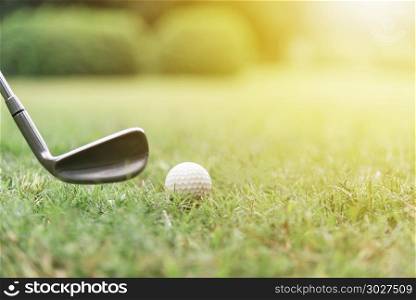 Golf ball with golf club on green grasses with sunlight.